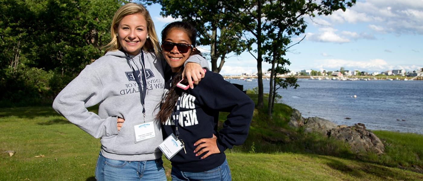 Two U N E students standing together by the water